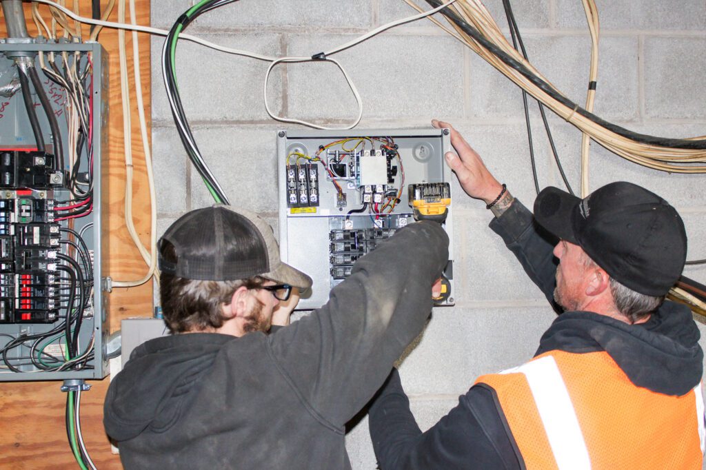 Two electricians installing a new control panel demonstrating professional electrical expertise and commitment to safety