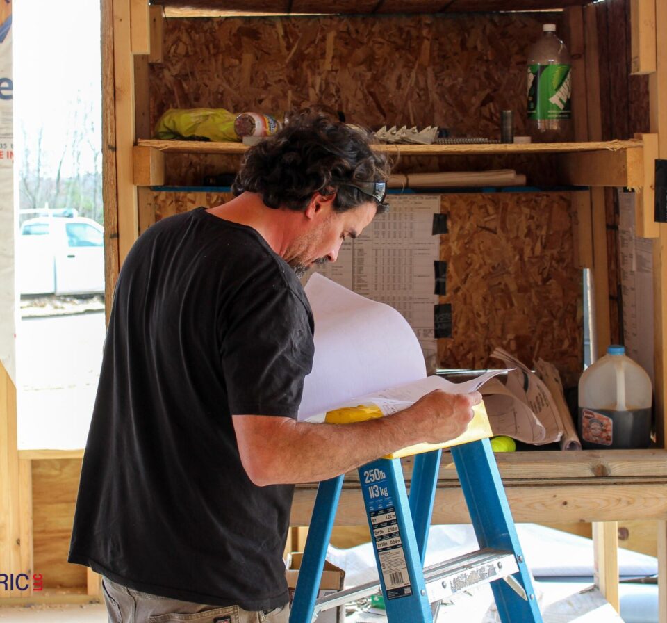 Contractor reviewing blueprint for electrical wiring installation in residential home